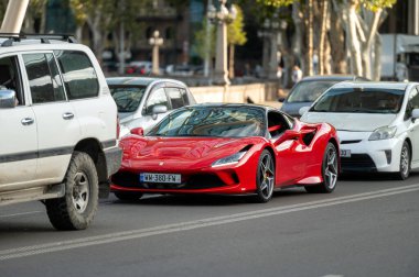 Tiflis, Gürcistan - 6 Ekim 2023: Kırmızı süper araba Ferrari F8 Örümcek bir şehir caddesinde.