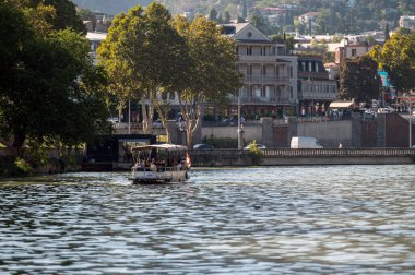 Tiflis, Gürcistan - 8 Ekim 2023: Turistler Mtkvari, Kura Nehri boyunca bir zevk gemisine biniyorlar.