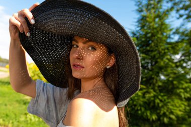 Zarif şapkalı güzel, şehvetli esmer portresi, yüzüne düşen gölgeler.