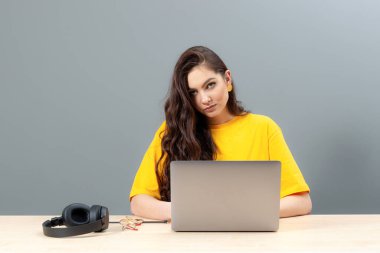 Genç bayan masada oturuyor, çalışırken modern teknolojiyi kullanıyor, online çalışma konsepti