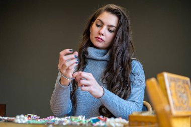 Aynada farklı takıları seçen ve deneyen bir kadının yansıması, yumuşak odak, yakın plan