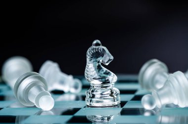 transparent glass chess on dark background, selective focus on knight piece, close-up