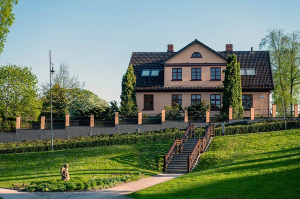 Yürüme yolları ve komşu binaları olan Kuldiga Eski Şehir Parkı, Letonya