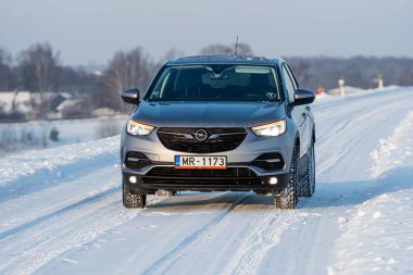 Riga, Letonya - 16 Ocak 2021: Gümüş 2019 Opel Grandland SUV Karlı bir yolda