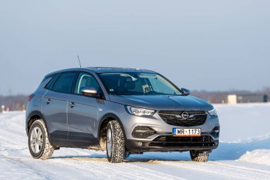 Riga, Letonya - 16 Ocak 2021: Gümüş 2019 Opel Grandland SUV Karlı bir yolda
