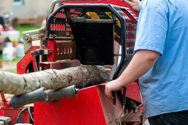 Bir adam odun öğütücüyle odun kesiyor, seçici bir odak noktası.