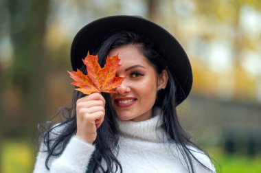 Elinde sonbahar yaprakları olan güzel bir genç kadının portresini yakından çek.