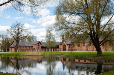 Güneşli bir bahar günü Litvanya 'da, göletin kıyısındaki Zagare malikanesi çiftliği.