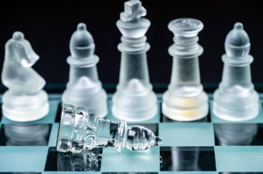 clear glass, transparent chess pieces on a checkerboard, selective focus, closeup, isolated on black