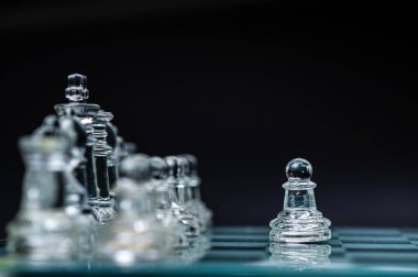 transparent glass chess on dark background, selective focus on pawn piece, close-up