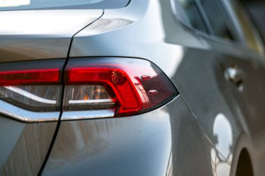 Geçmişi bulanık gümüş renkli bir arabanın arka lambasına yakın çekim..