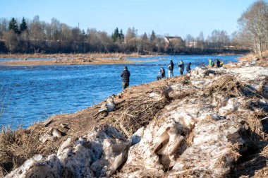 Kuldiga, Letonya - 3 Mart 2024: Balıkçılar baharın başlarında Venta nehrinin karla kaplı kıyılarında balık yakalıyor.