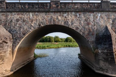 Altında akan sular olan taş köprü nehri geçiyor. Kandava, Letonya