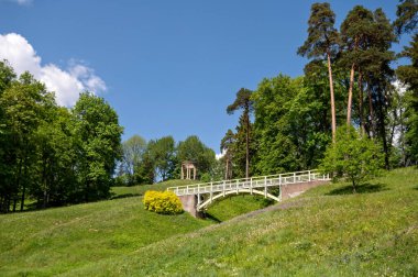 Letonya 'nın Aluksne kasabasındaki Temple Hill parkında granit kubbe ve tahta yaya köprüsü.