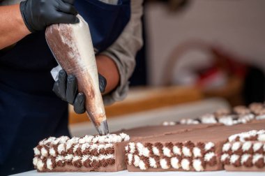Bir fırıncı çikolatalı pasta süsler. Seçici odak ve kopyalama alanı olan arkaplan.