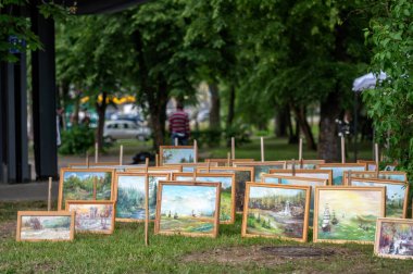 Dobele, Letonya - 8 Haziran 2024: Çerçevelenmiş tablolar yaz pazarında bir parkta sergileniyor