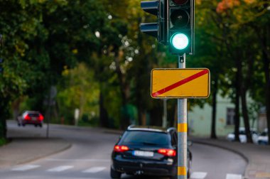 Sonbahar şehrinin kapanmış arka planına yeşil ışık yakılmış trafik semaforu, yakın plan