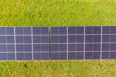 Güneş panelleri sıra sıra dizilmiş, çimen tarlasında..