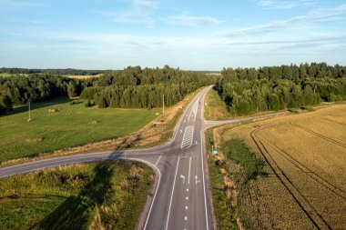 Kırsal bir yol kavşağı ve ana yolda giden bir araba..