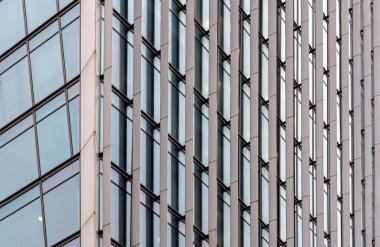 Modern cam bir binanın gösterişli yüzü bulutlu gökyüzünü yansıtır..