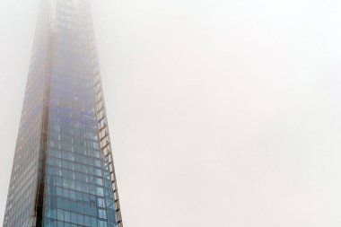 Yoğun siste gizlenmiş, gizemli bir atmosfer yaratan yüksek bir bina..