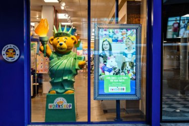 New York, ABD - 6 Haziran 2019: Özgürlüğe benzeyen bir ayı heykeli neşeli ziyaretçilerin bulunduğu bir atölye girişinde duruyor.