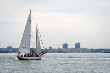 New York, ABD - 7 Haziran 2019: Bir yelkenli bulutlu gökyüzünün altında liman suyunda süzülüyor.