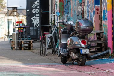 Riga, Letonya - 30 Eylül 2020: Park halindeki bir scooter renkli bir sokak sanatının yanında canlı bir açık hava alanında dinleniyor.