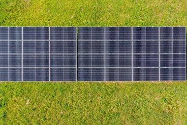 Güneş panelleri sıra sıra dizilmiş, çimen tarlasında..