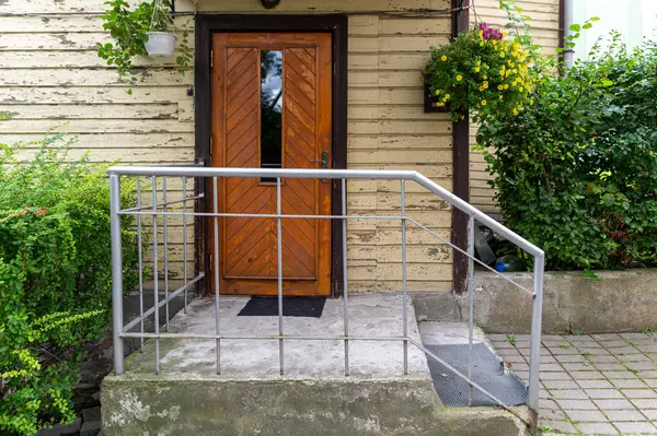 stock image Tukums, Latvia - August 22, 2024: A charming entrance features a wooden door surrounded by greenery.