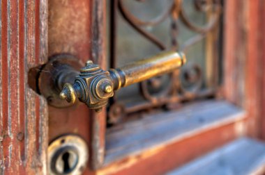 Pirinçten bir kapı koluna yakın çekim ve demir işçiliği detaylarıyla birlikte eski bir ahşap kapıya kilitlenme..