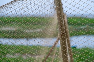 Çimlerin üzerine uzanan bir balık ağı berrak bir gökyüzünün altında sakin bir nehrin yanında..