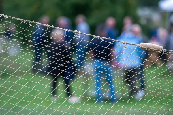 stock image People gather and chat while a net separates them from the event area.