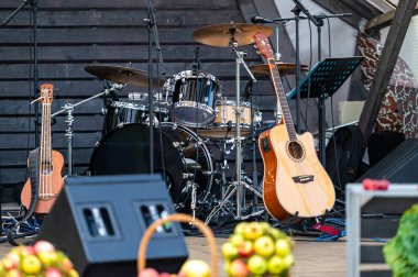 A stage is prepared with drums and guitars, awaiting the start of a live music event. clipart