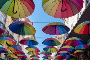 Güneşli bir günde canlı bir sokakta asılı renkli şemsiyeler