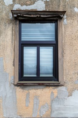 Köy duvarındaki yıpranmış alçı çerçeveli klasik bir pencere karakter ve yaşı gösterir.