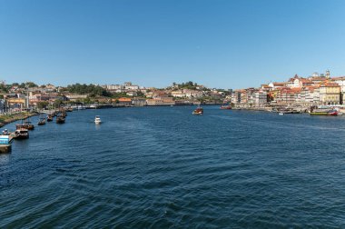 Porto, Portekiz - 13 Eylül 2024: Güneşli bir günde arka planda canlı bir Porto ile Douro Nehri 'nde tekneler dolaşır