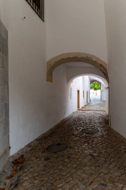 Sintra, Portugal - September 9, 2024 : A quiet, narrow alleyway with cobblestone pavement, bordered by white buildings. clipart