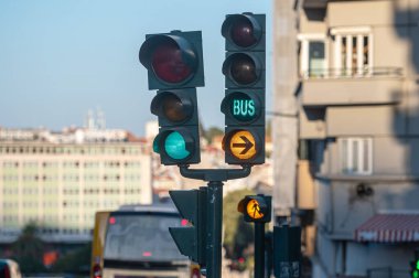 Trafik işaretleri yoğun bir kavşakta otobüs şeridi iznini ve yaya geçişini gösterir.