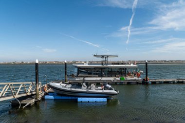 Güneşli bir günde nehir kıyısındaki bir rıhtıma yanaşan turist teknesi.