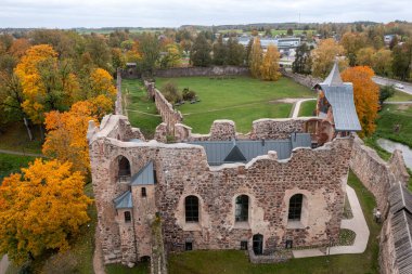 Ancient castle ruins stand amidst vibrant autumn foliage in a tranquil setting. clipart