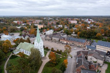 Aerial view of an Latvian town features a historic church and colorful autumn trees. clipart