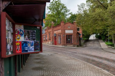 Talsi, Latvia - September 1, 2024:  A quiet town street featuring cobblestones and historic red brick architecture. clipart