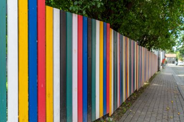 Parlak, çok renkli ahşap bir çit yerleşim yerinin kaldırımını çiziyor, davetkar bir manzara yaratıyor..