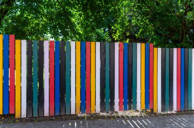 Güneşli bir günde canlı bir şehrin kaldırımında renkli ahşap çitler.
