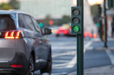 Yeşile dönen trafik lambasında bir araba bekliyor. Güvenli geçiş olduğunu gösteriyor..