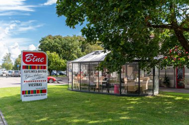 Talsi, Latvia - September 1, 2024: A bistro with a glass enclosure surrounded by greenery on a bright, sunny day. clipart