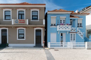 Costa Nova, Portekiz - 11 Eylül 2024: Farklı renklere sahip iki hoş hostel kıyıdaki bir mahallede yan yana duruyor.