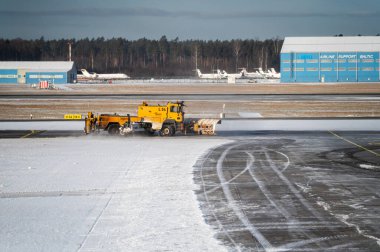 Riga, Letonya - 15 Şubat 2025: Ağır makineler kışın Riga uluslararası havaalanındaki pistte kar temizliyor.