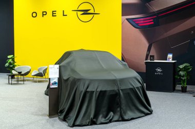 Riga, Letonya - 25 Nisan 2025: Kapalı Yeni Opel Mokka cesur arkaplan ve şık ekran ile otomobil fuarında ifşaat etmeyi bekliyor.